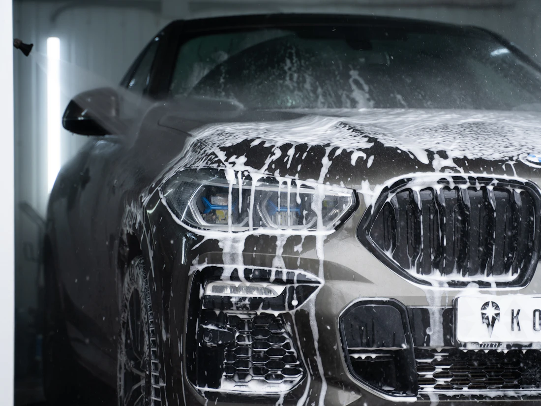 A dark car covered in thick white soap foam